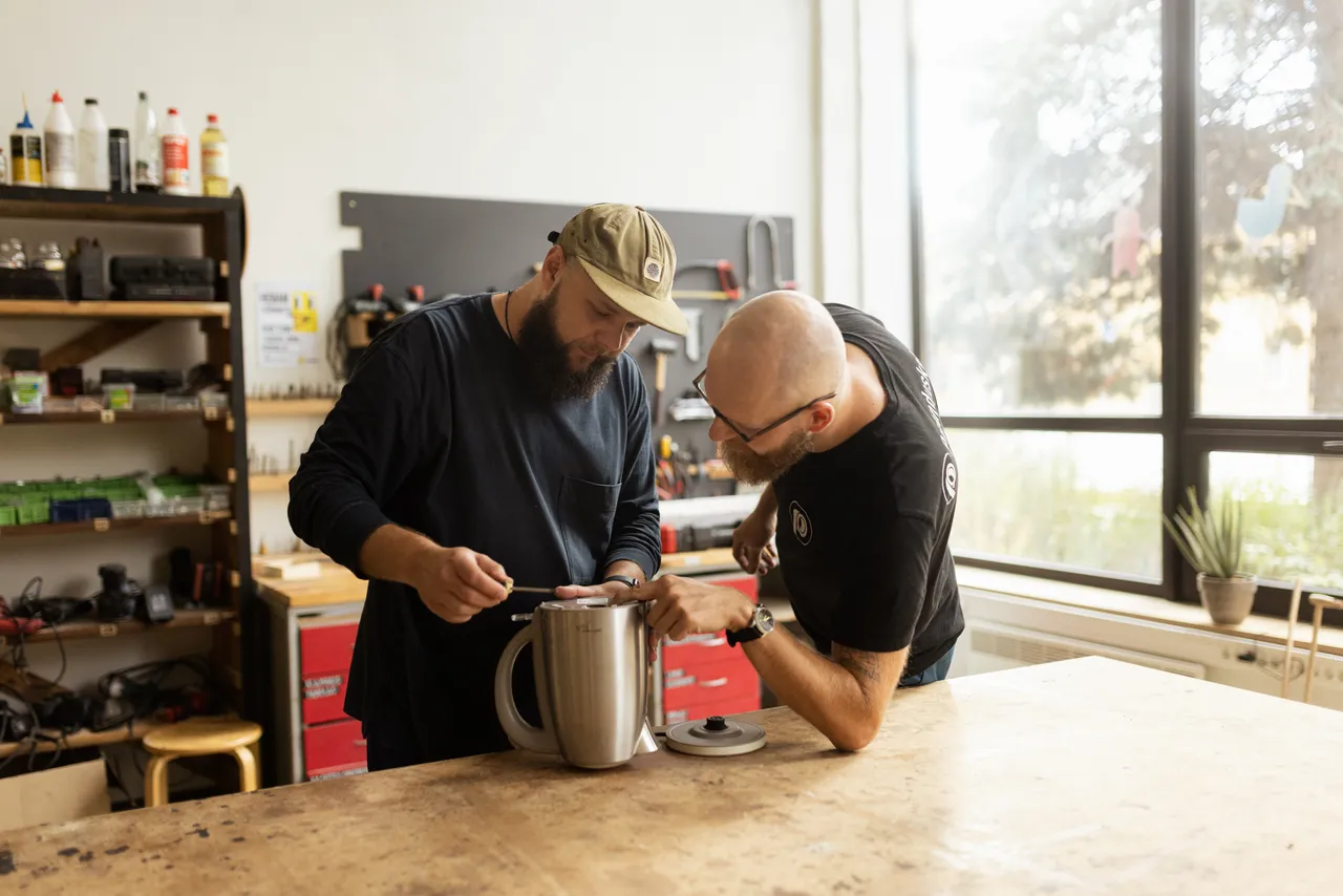 Men repairing electric kettle in workshop