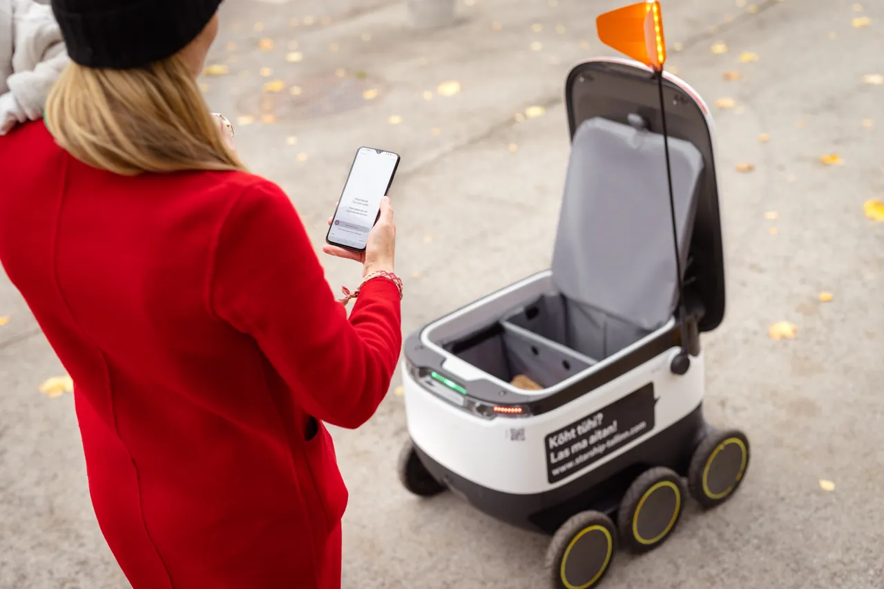 Woman with baby receiving delivery by Starship robot