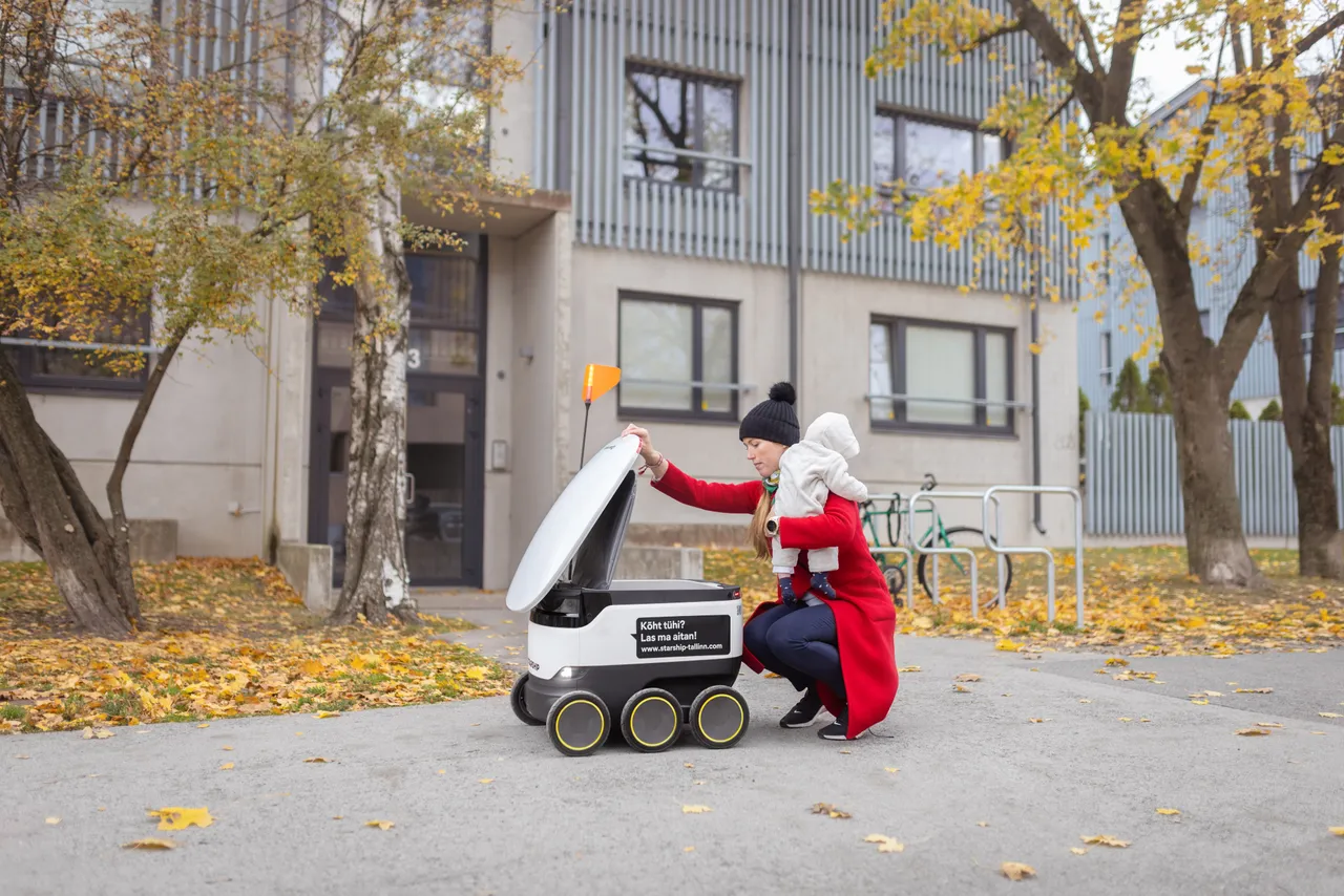 Woman with baby receiving delivery by Starship robot