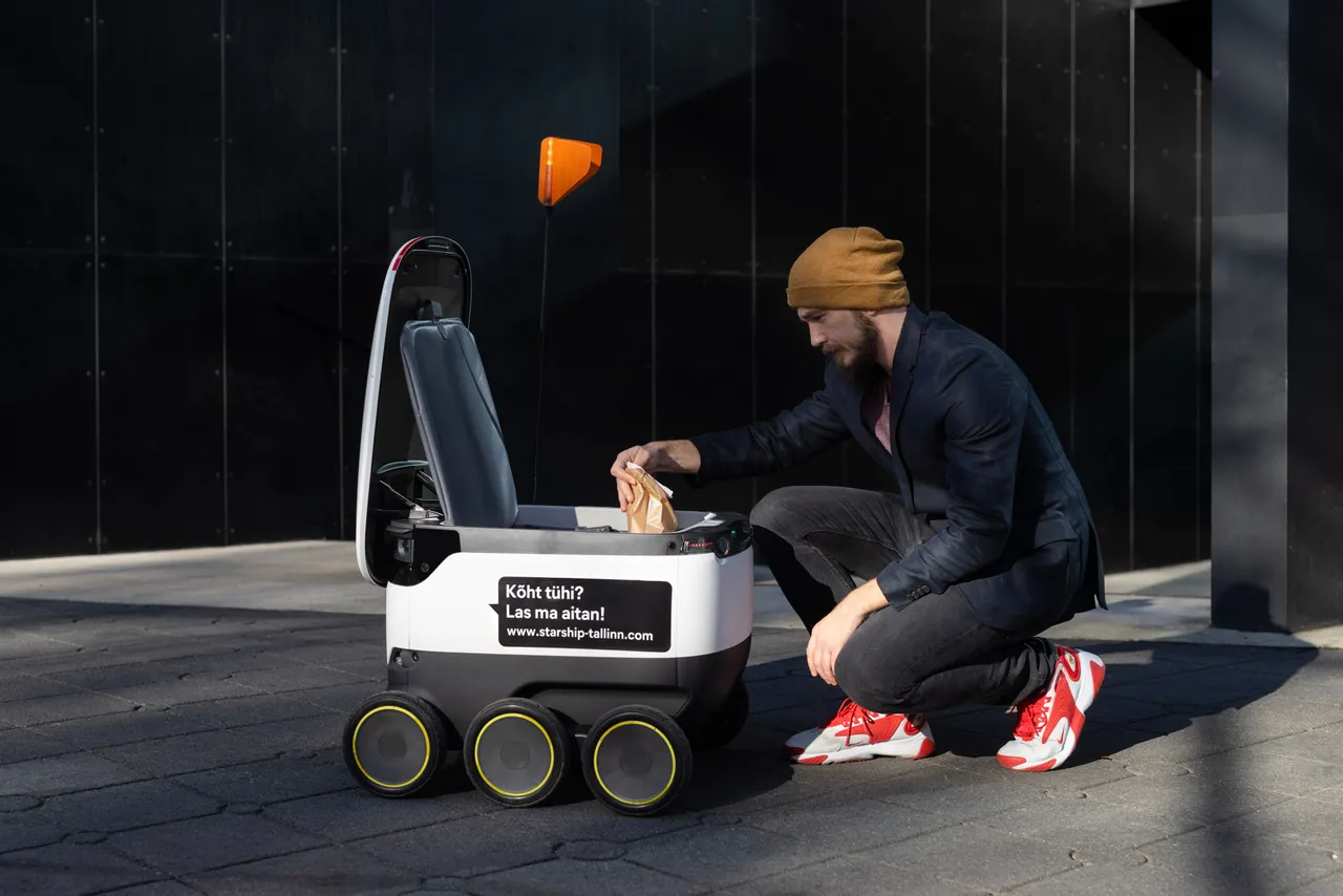 Man taking package from Starship delivery robot