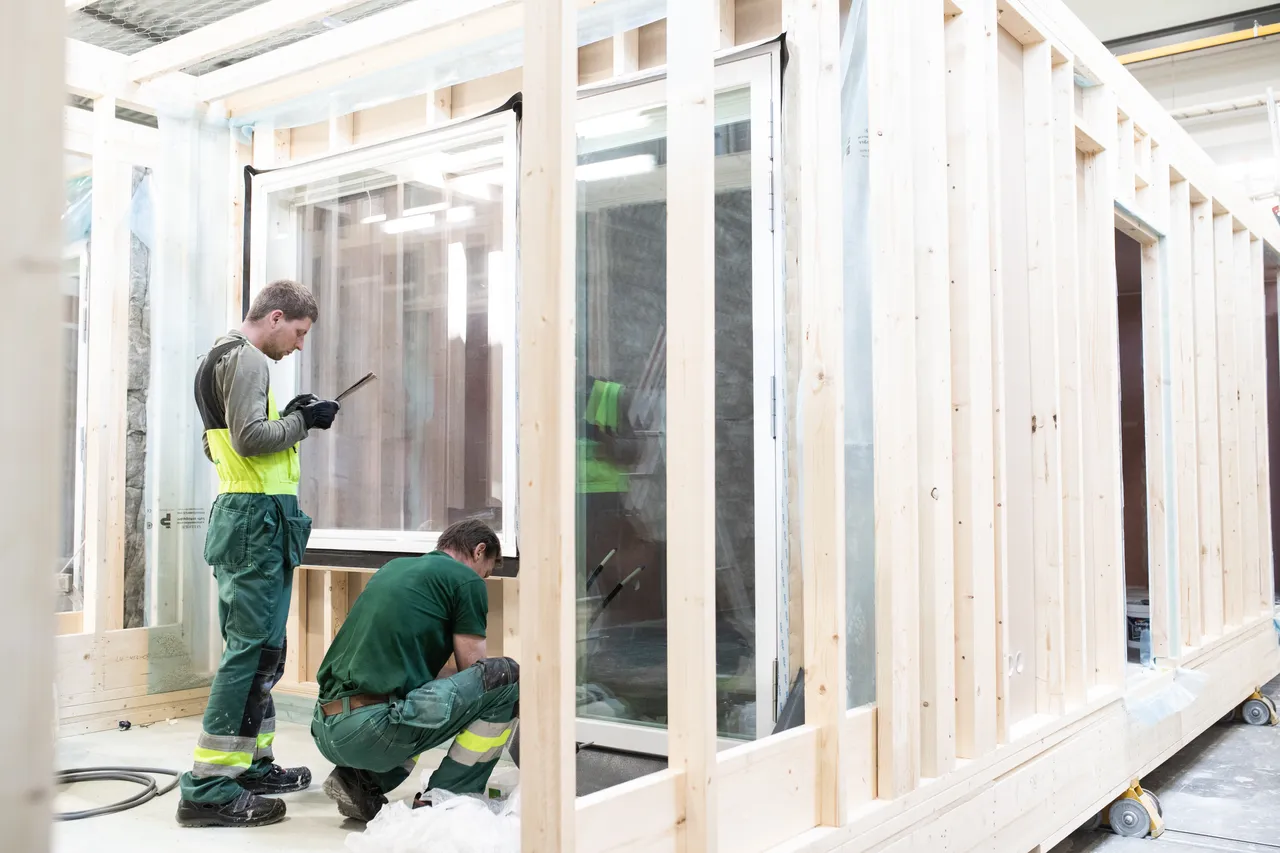 Men installing windows to wooden modular house