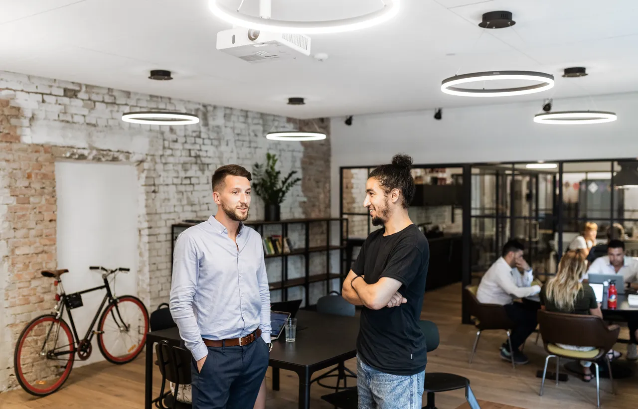 Two men having a conversation in open office