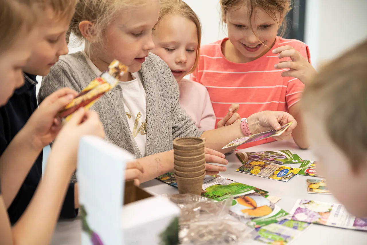 Excited children planting vegetables in classroom