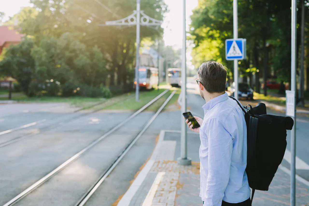 Man waiting tram phone