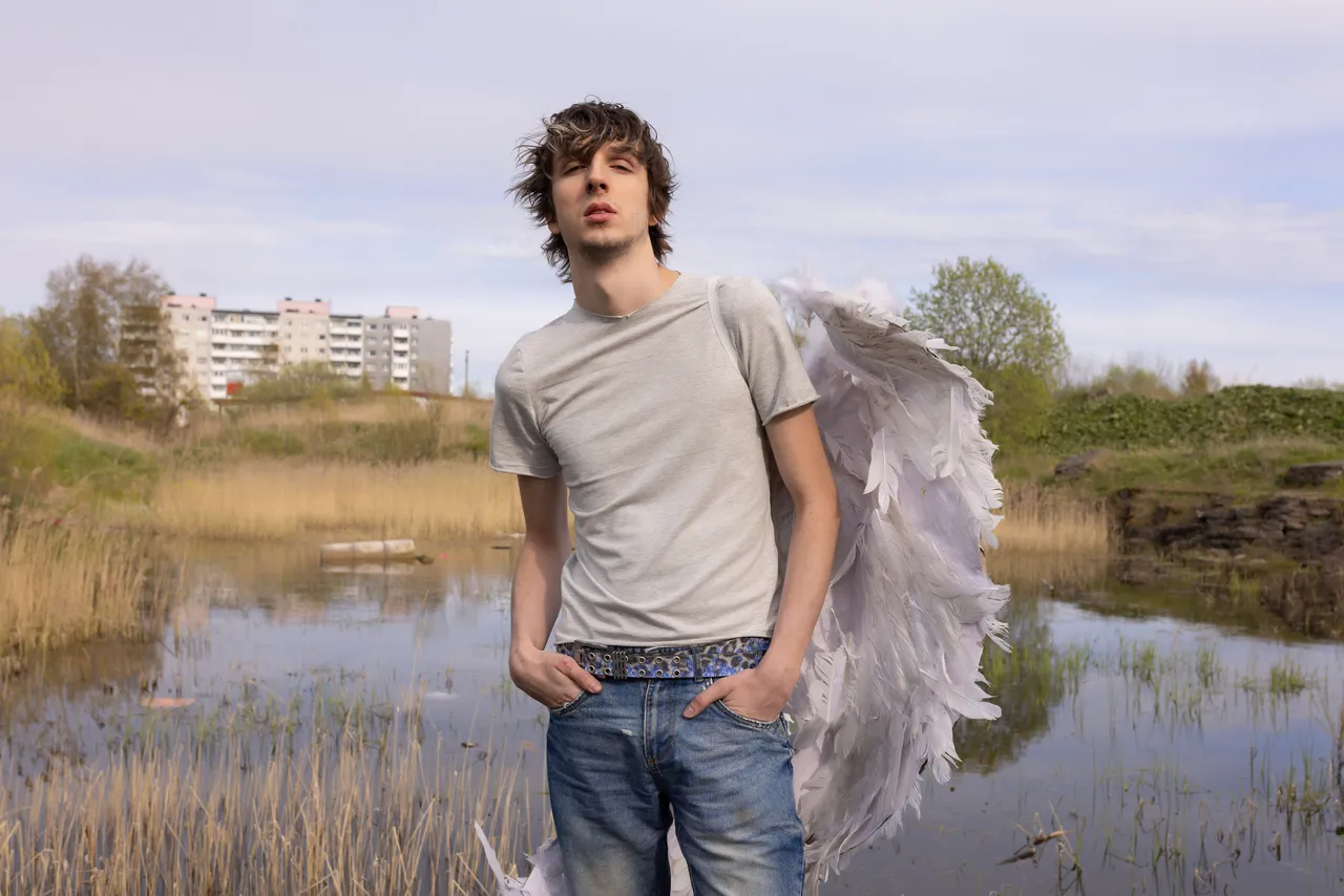 Mihhail Zigadlo, founder and creative director of Racer Worldwide, posing outdoors with angel wings as part of a fashion concept photo.