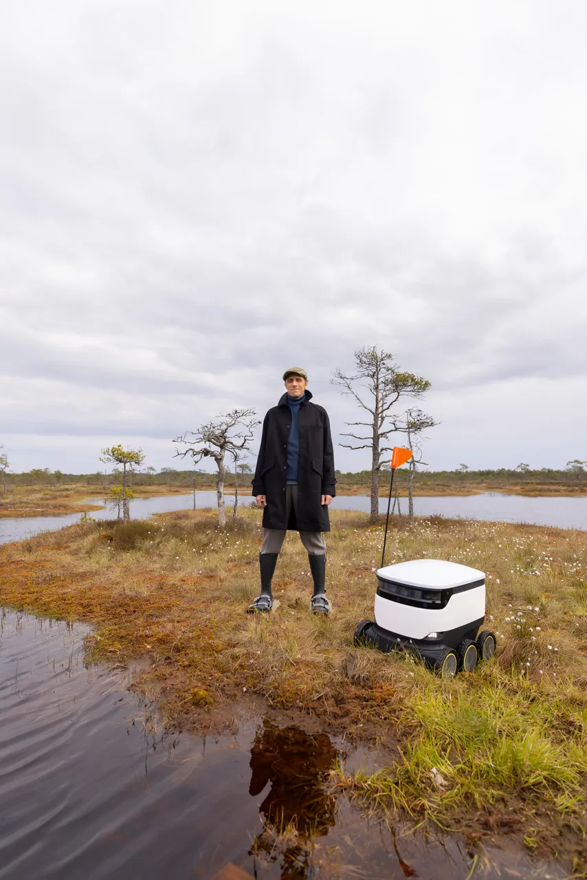 Ahti Heinla standing in an Estonian bog next to a Starship delivery robot.