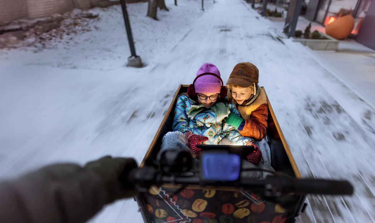 A girl and boy sitting in a cargo bike