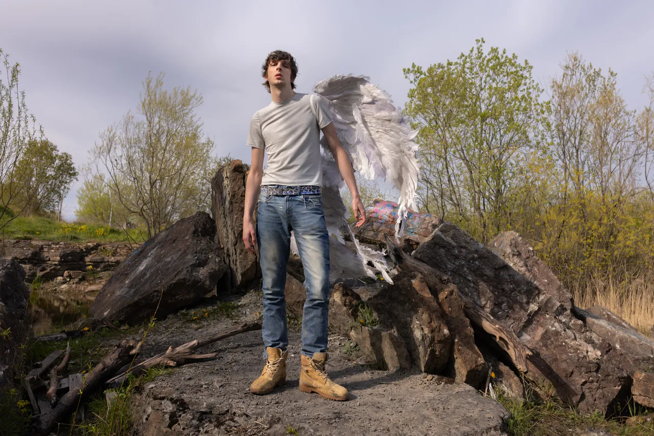 Mihhail Zigadlo, founder and creative director of Racer Worldwide, posing outdoors with angel wings as part of a fashion concept photo.