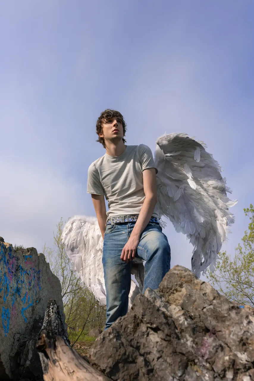 Mihhail Zigadlo, founder and creative director of Racer Worldwide, posing outdoors with angel wings as part of a fashion concept photo.