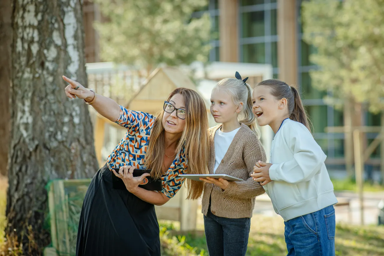 Teacher guiding students outdoors with tablet