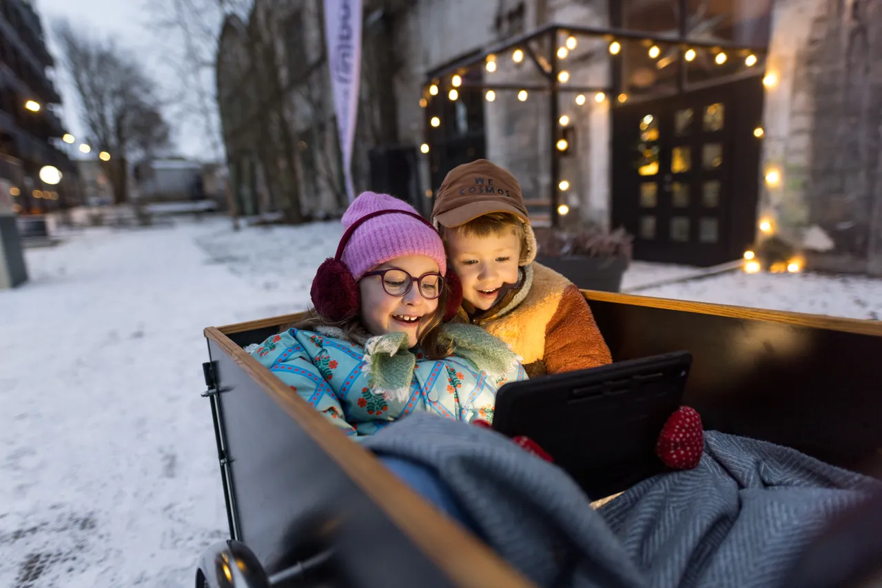 A girl and boy sitting in a cargo bike