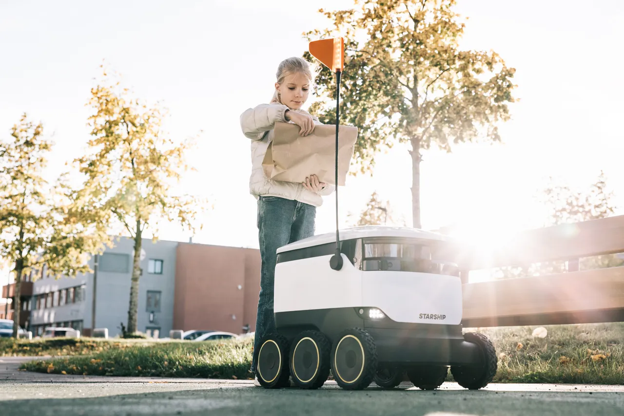 Girl receiving package from Starship robot
