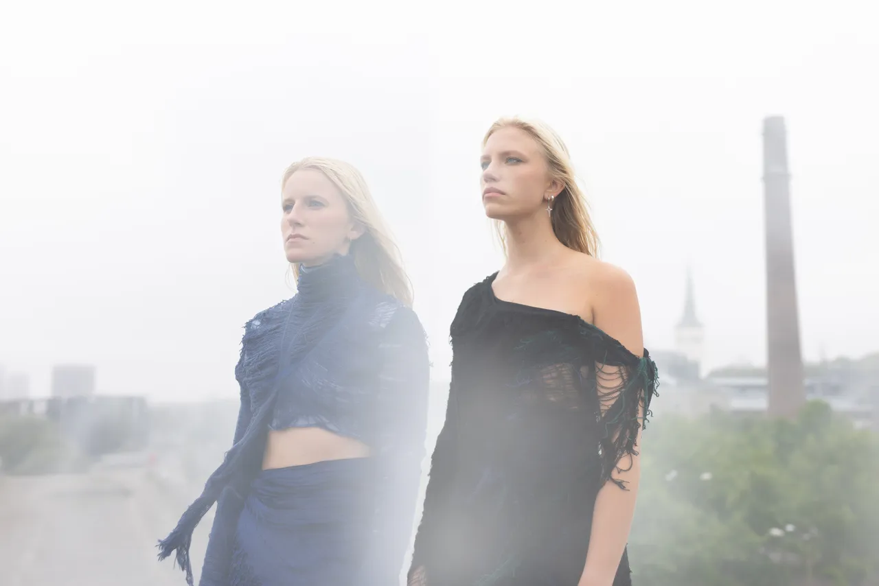 Two women from Duo Ruut, Katariina Kivi and Ann-Lisett Rebane, playing kannel outdoors in a misty urban setting.