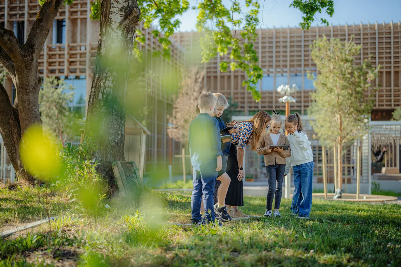 Children and teacher using tablet outdoor