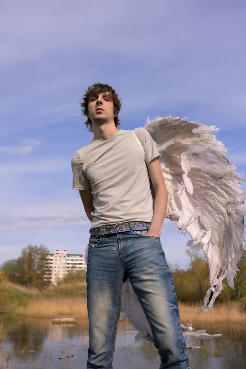 Mihhail Zigadlo, founder and creative director of Racer Worldwide, posing outdoors with angel wings as part of a fashion concept photo.