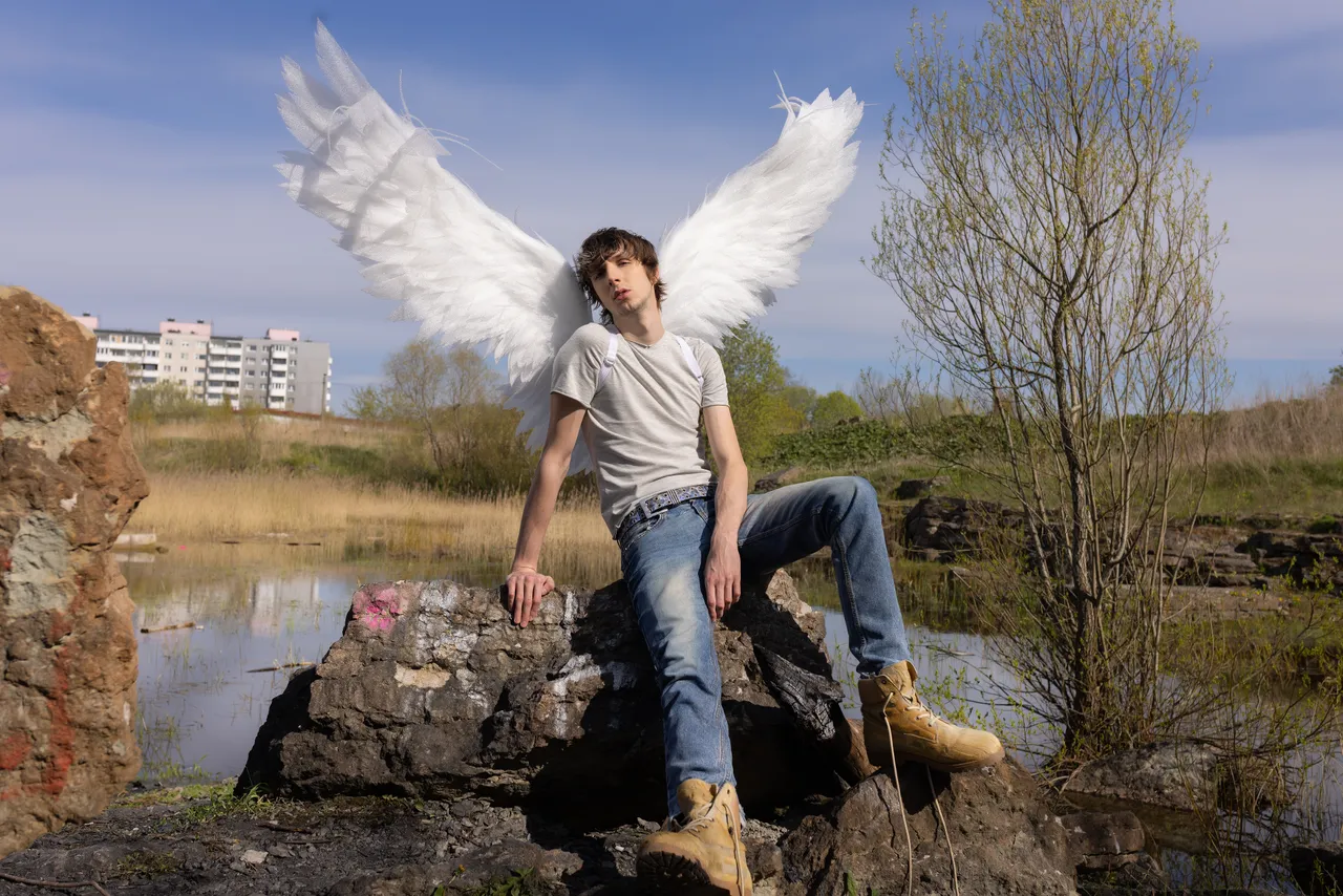Mihhail Zigadlo, founder and creative director of Racer Worldwide, posing outdoors with angel wings as part of a fashion concept photo.
