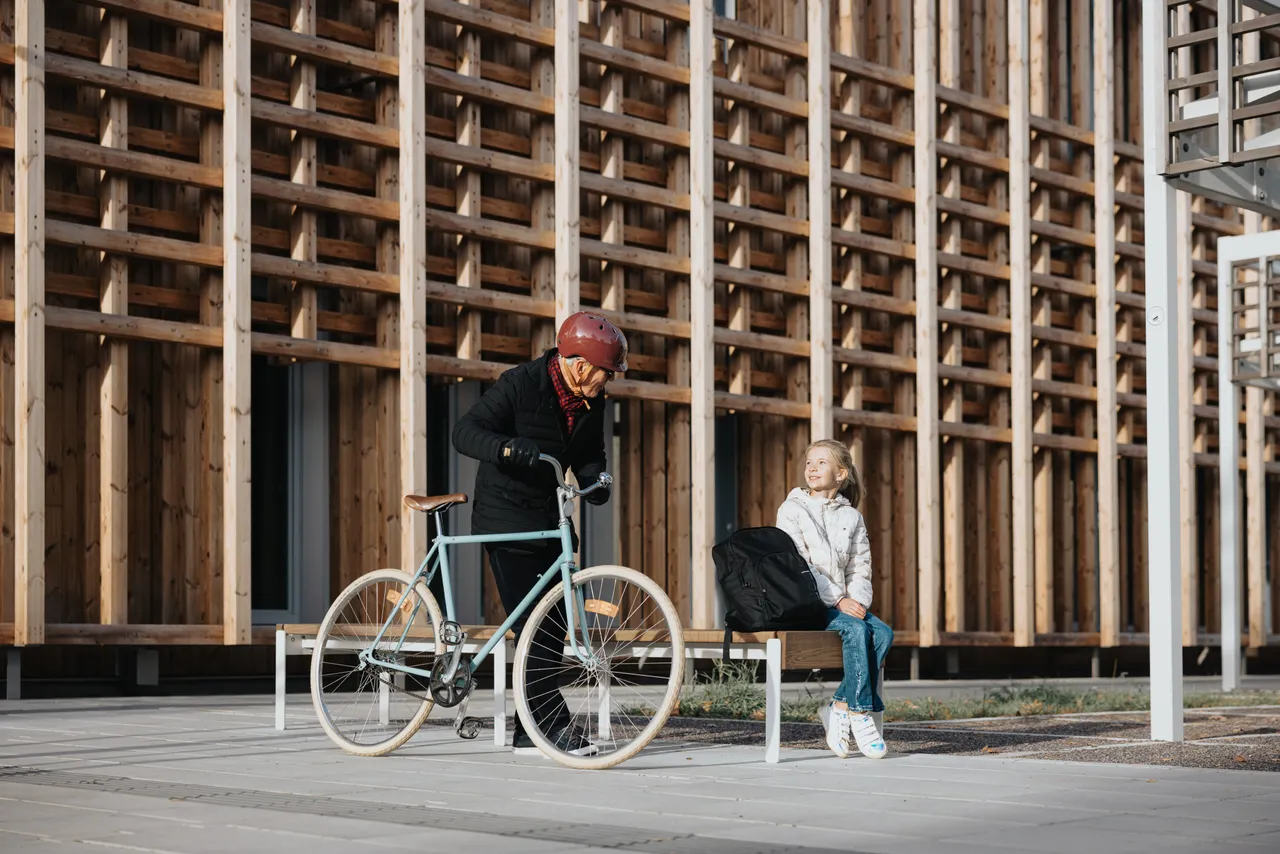 Grandfather picking up granddaughter from school with a bike