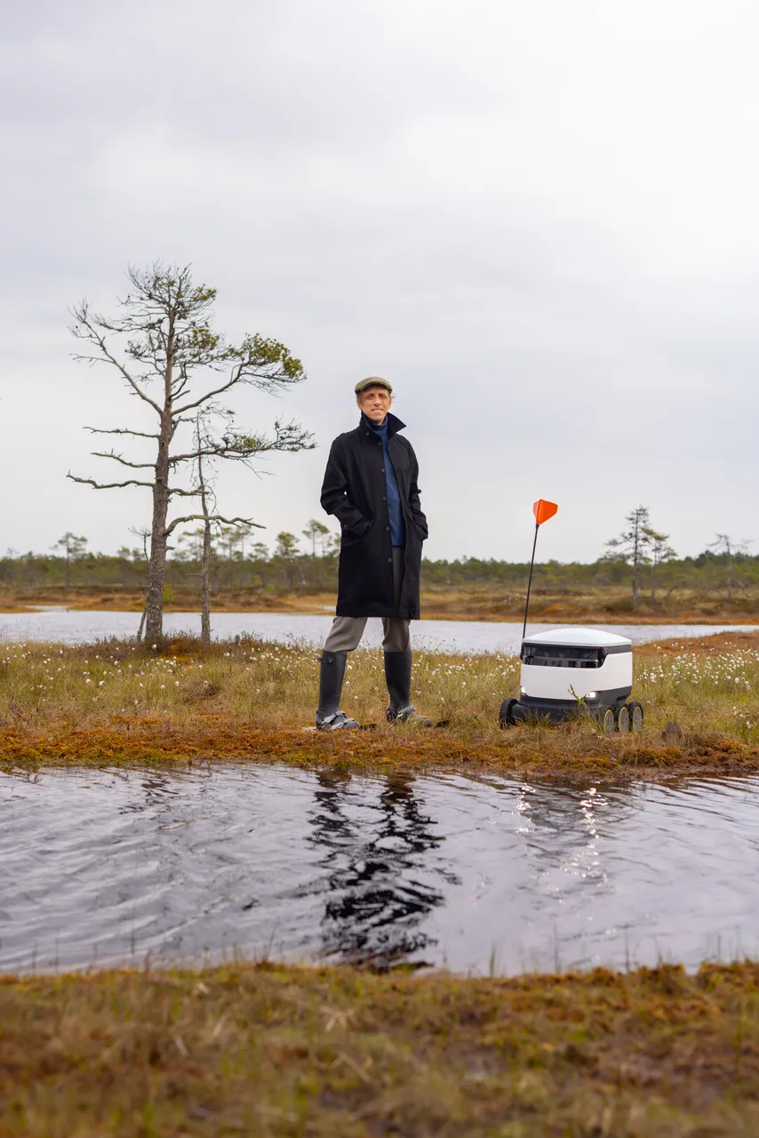 Ahti Heinla standing in an Estonian bog next to a Starship delivery robot.