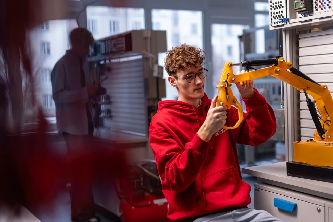 Student working on a robotic arm in a tech lab