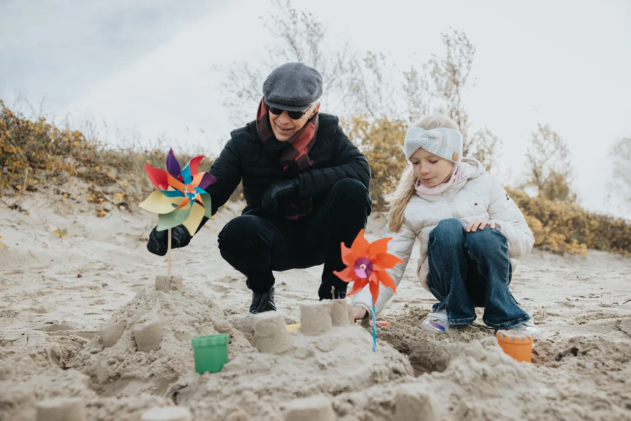Girl and her grandfather playing on the beach