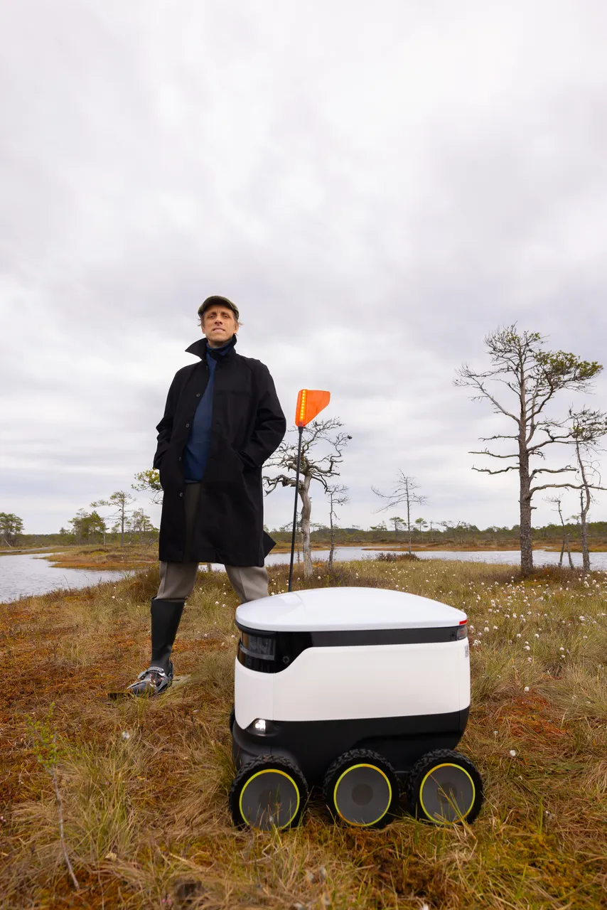 Ahti Heinla standing in an Estonian bog next to a Starship delivery robot.