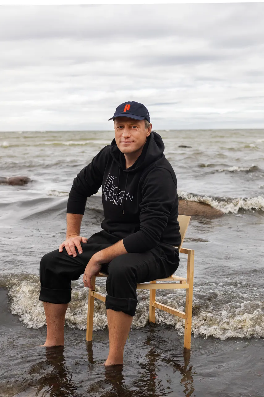 Taavi Kotka, Estonian entrepreneur and digital society pioneer, sitting barefoot on a chair in the sea.