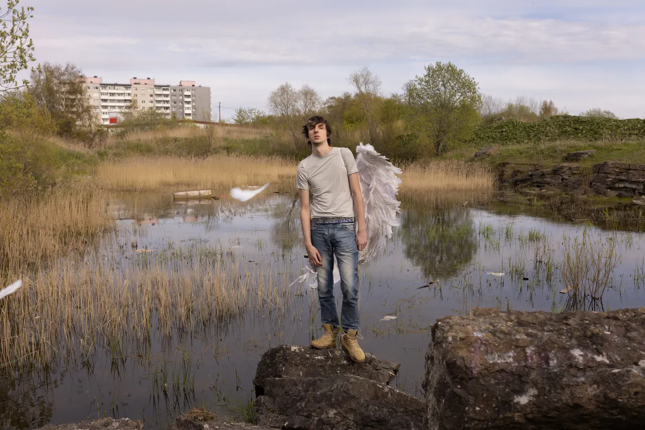 Mihhail Zigadlo, founder and creative director of Racer Worldwide, posing outdoors with angel wings as part of a fashion concept photo.