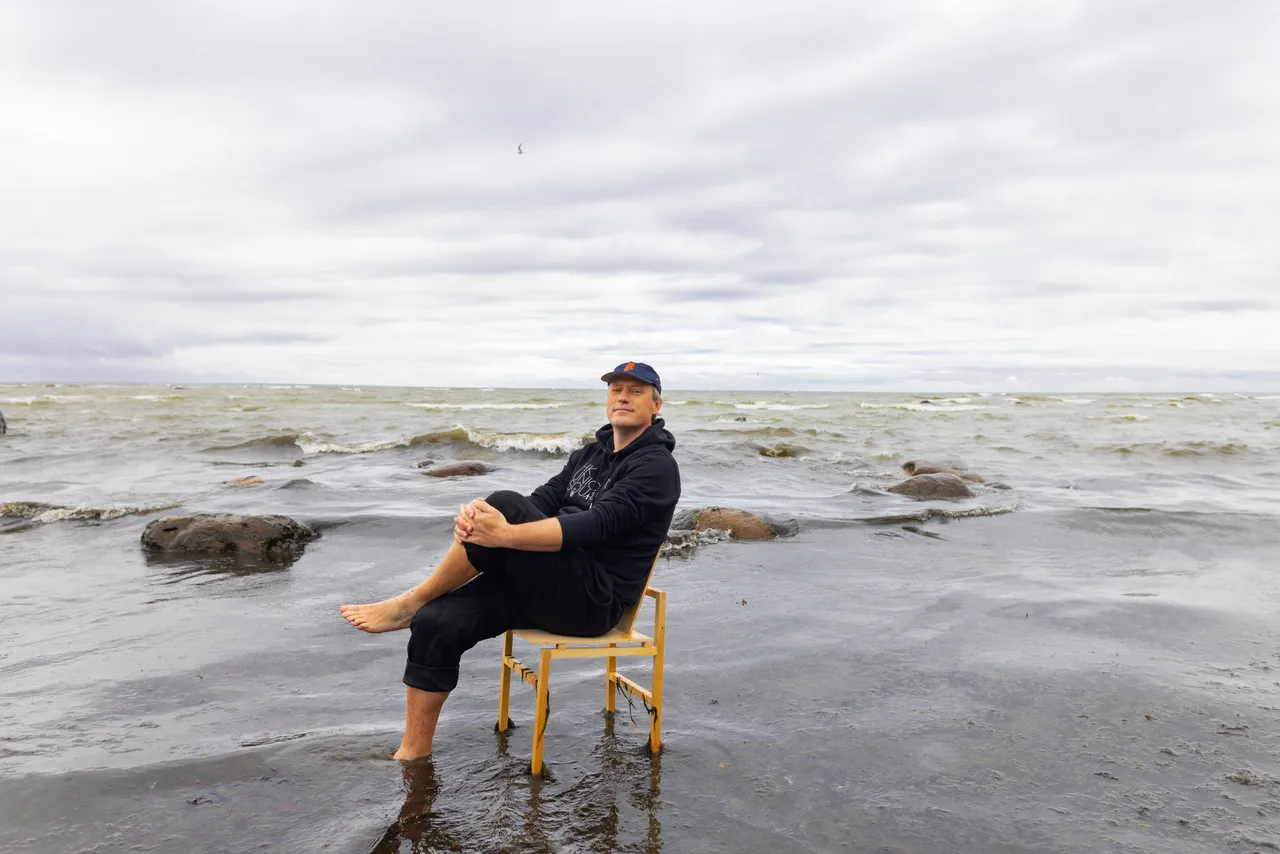 Taavi Kotka, Estonian entrepreneur and digital society pioneer, sitting barefoot on a chair in the sea.