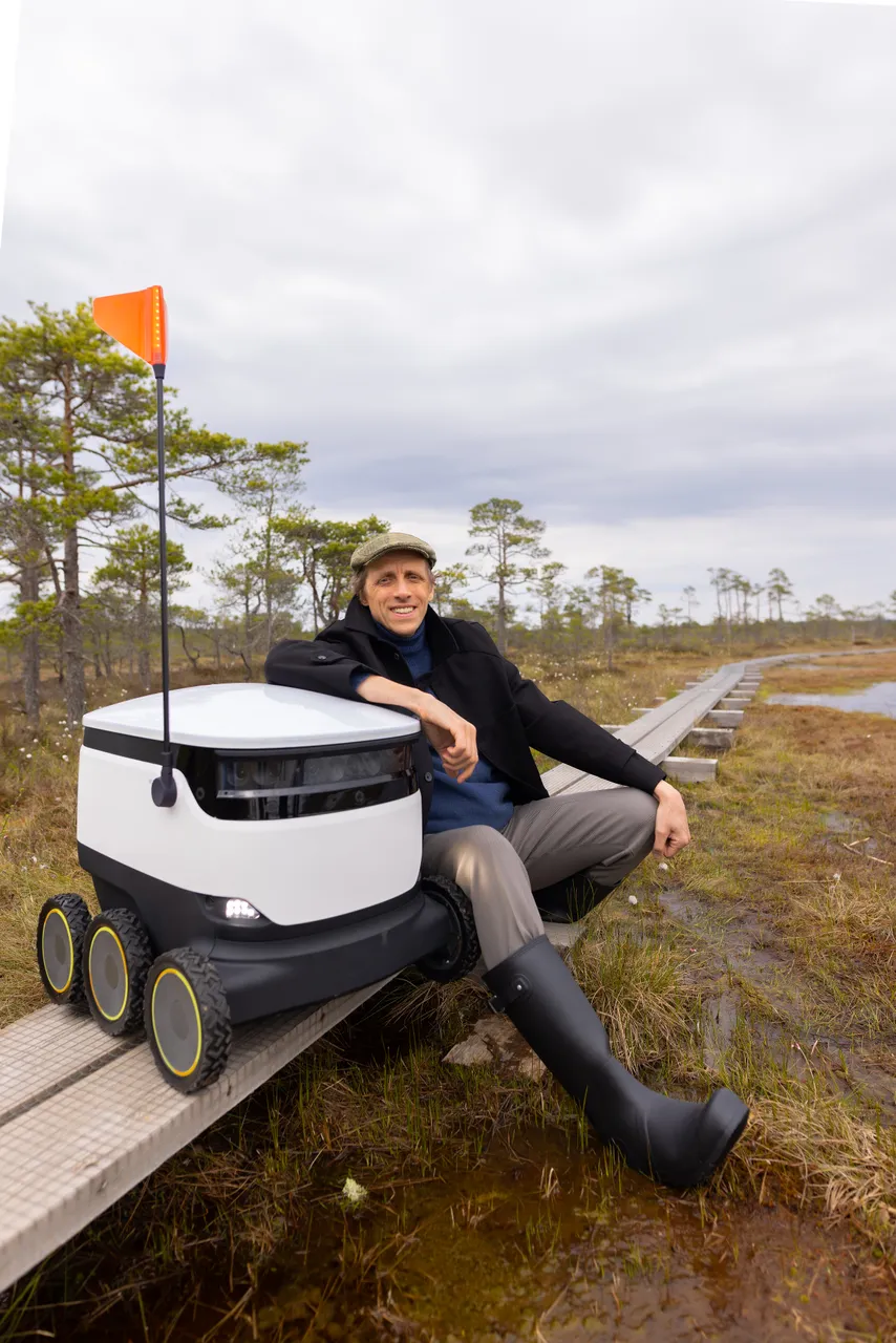 Ahti Heinla standing in an Estonian bog next to a Starship delivery robot.