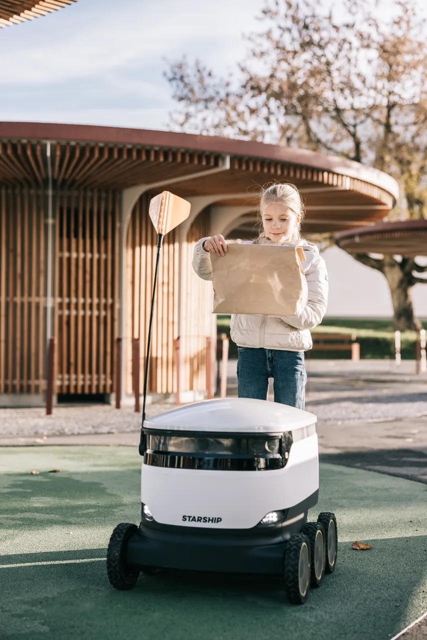 Girl receiving package from Starship robot