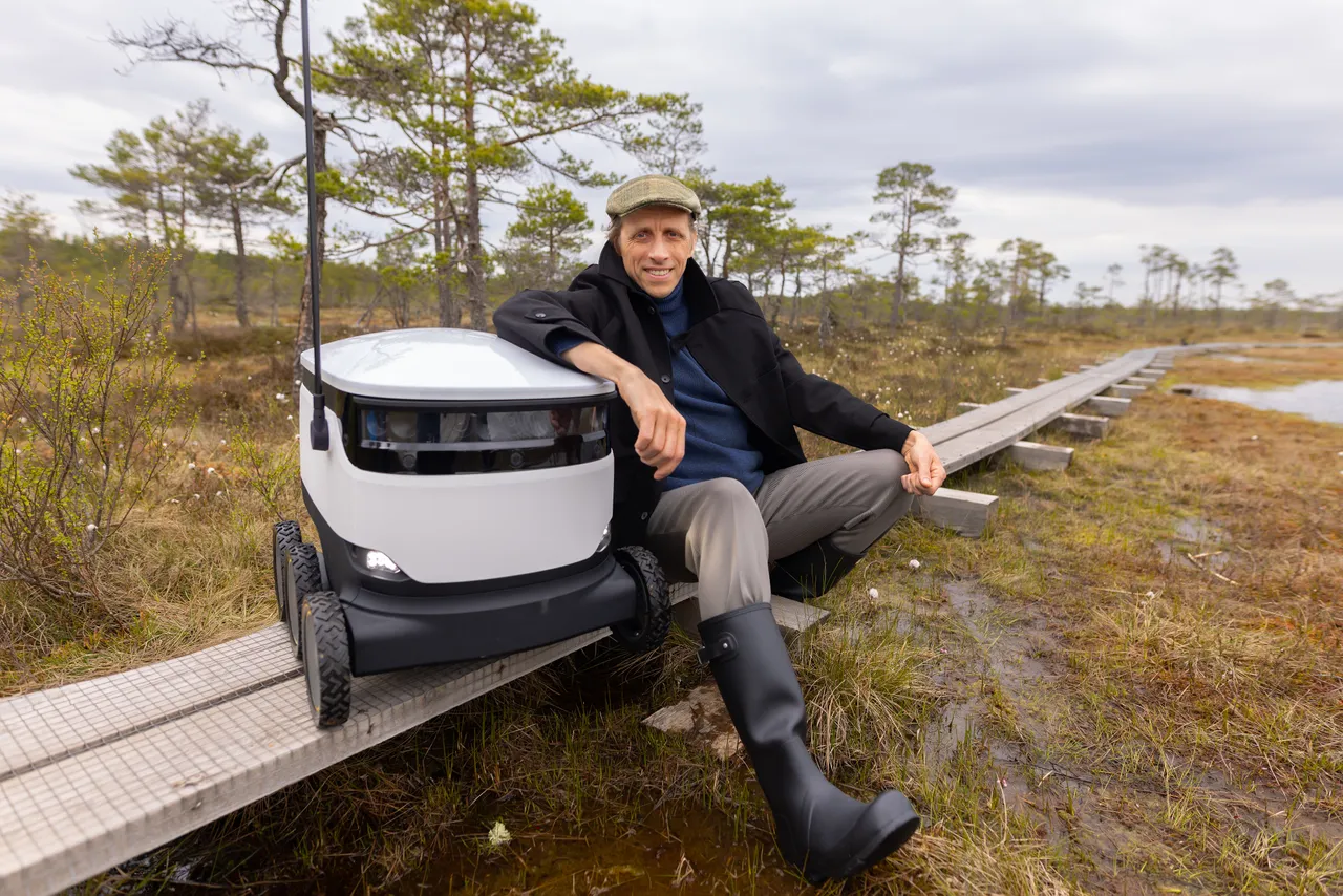 Ahti Heinla standing in an Estonian bog next to a Starship delivery robot.